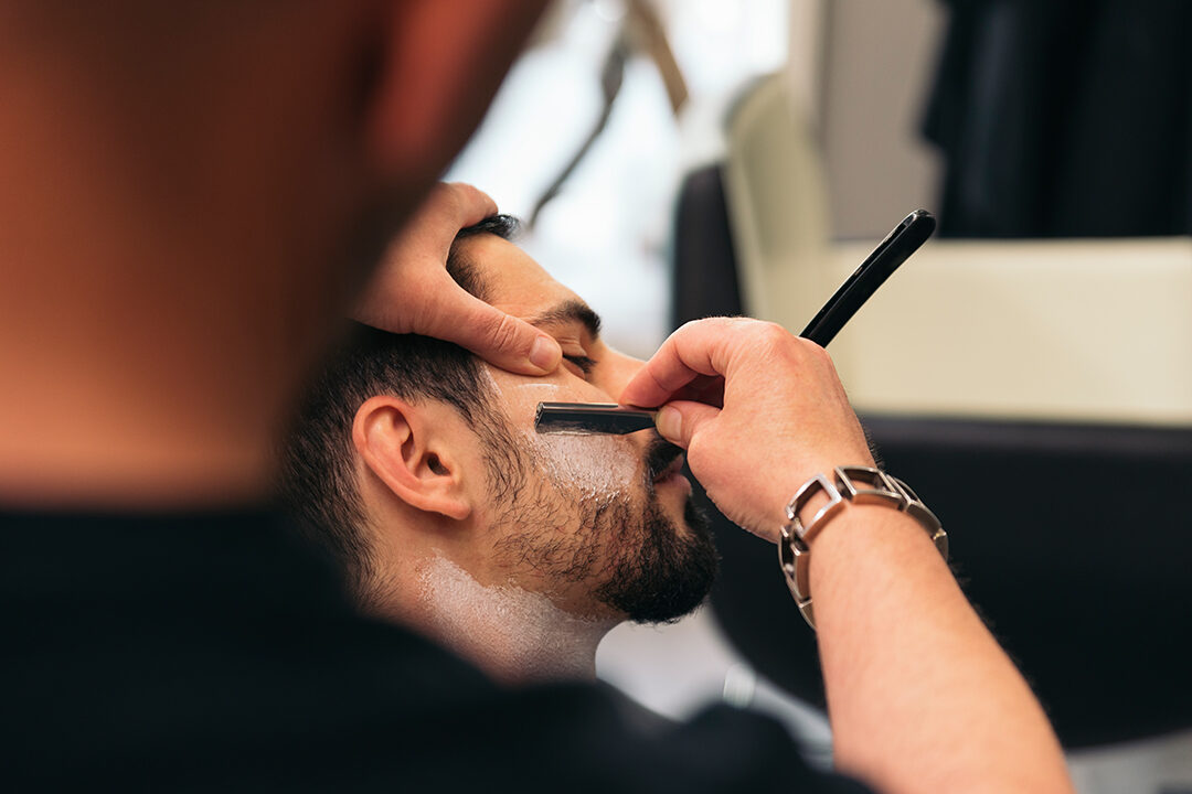 Young Bearded Man Getting Beard Haircut With A Razor By Barber. Barbershop Theme